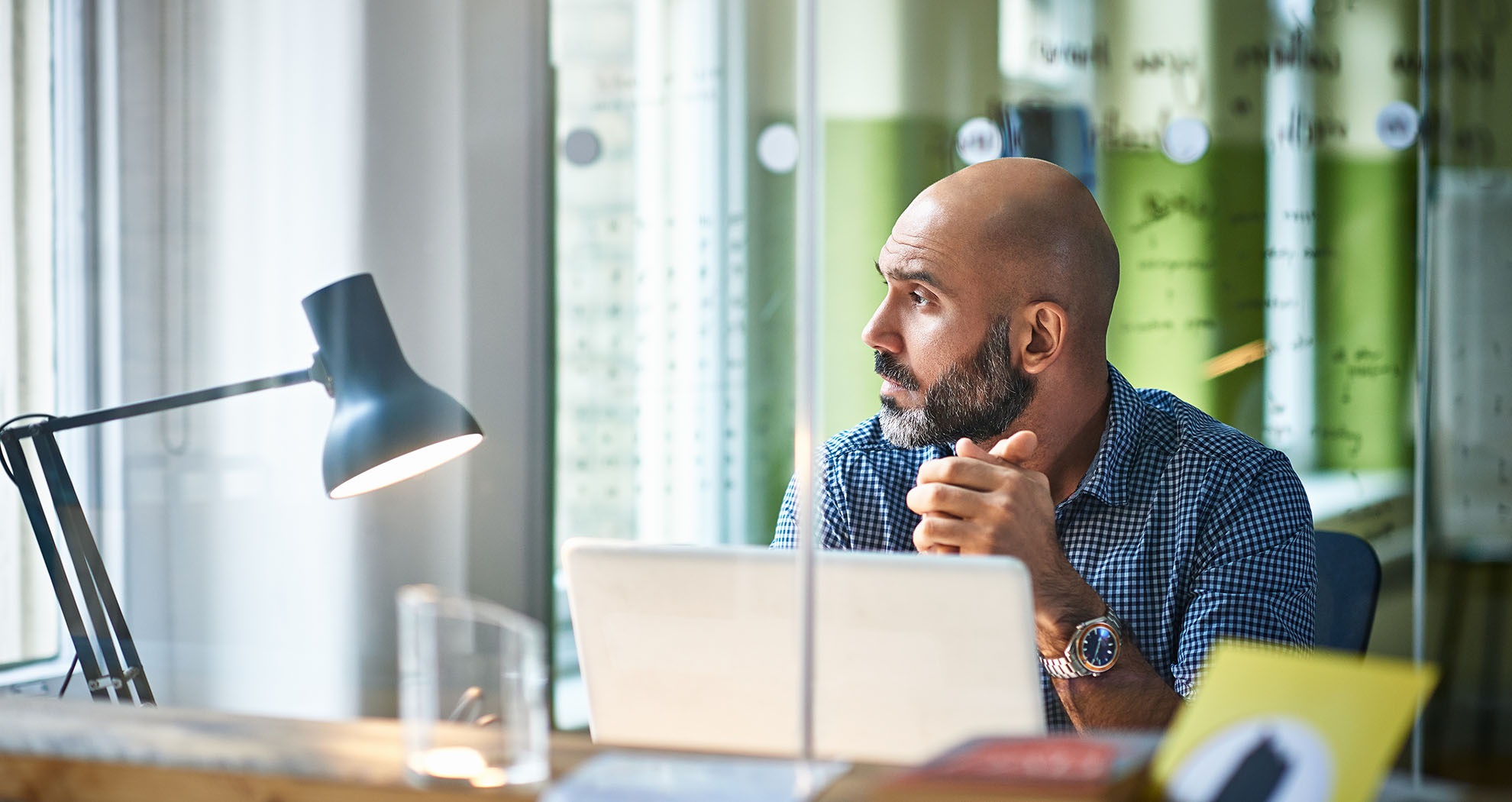 Man sitting at a laptop looking out the office window