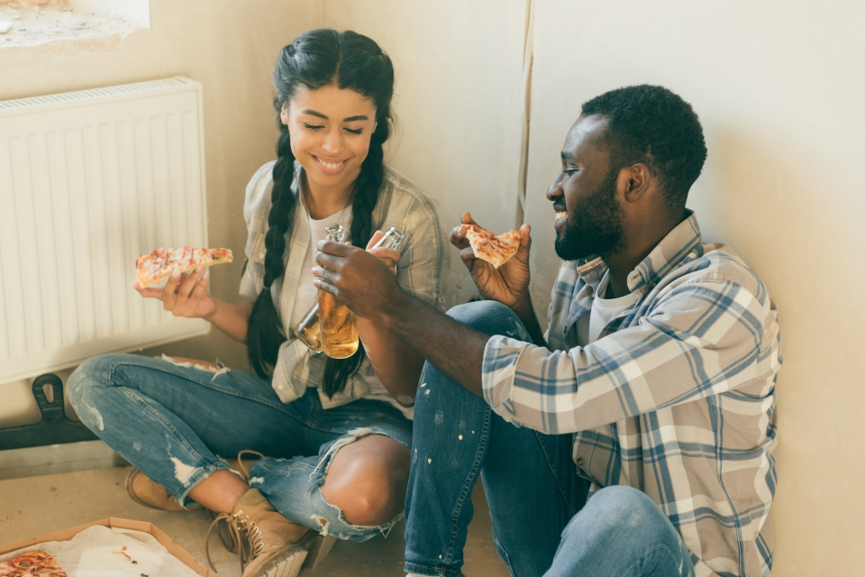 Couple on the floor of their home eating pizza and drinking.