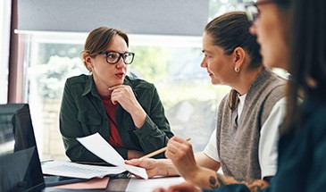 3 oficce workers sat round a table, dicussing how to get started