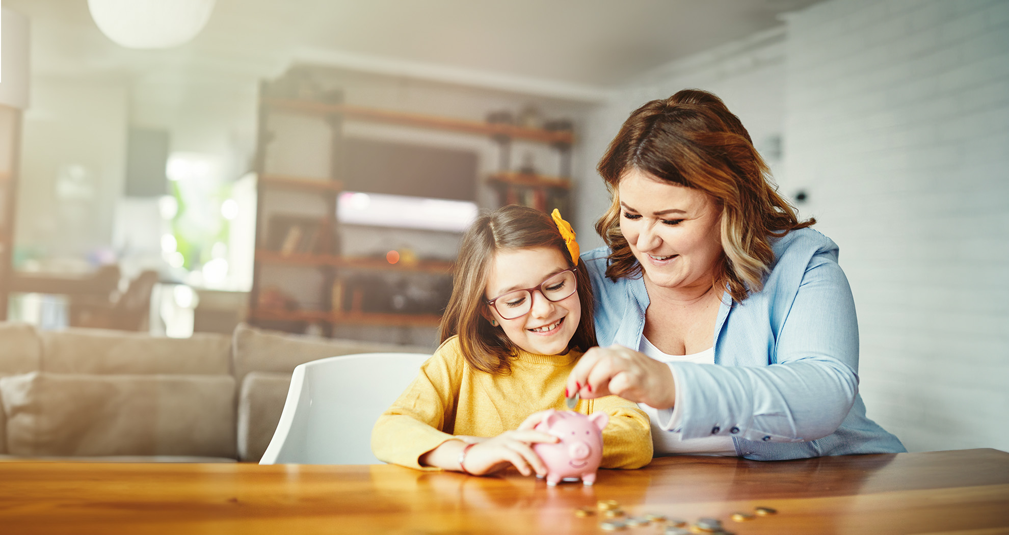 Mother and daughter using a piggy bank at a table